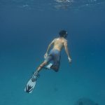 man freediving with flippers underwater