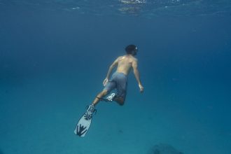 man freediving with flippers underwater
