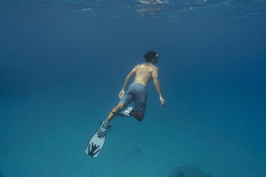 man freediving with flippers underwater
